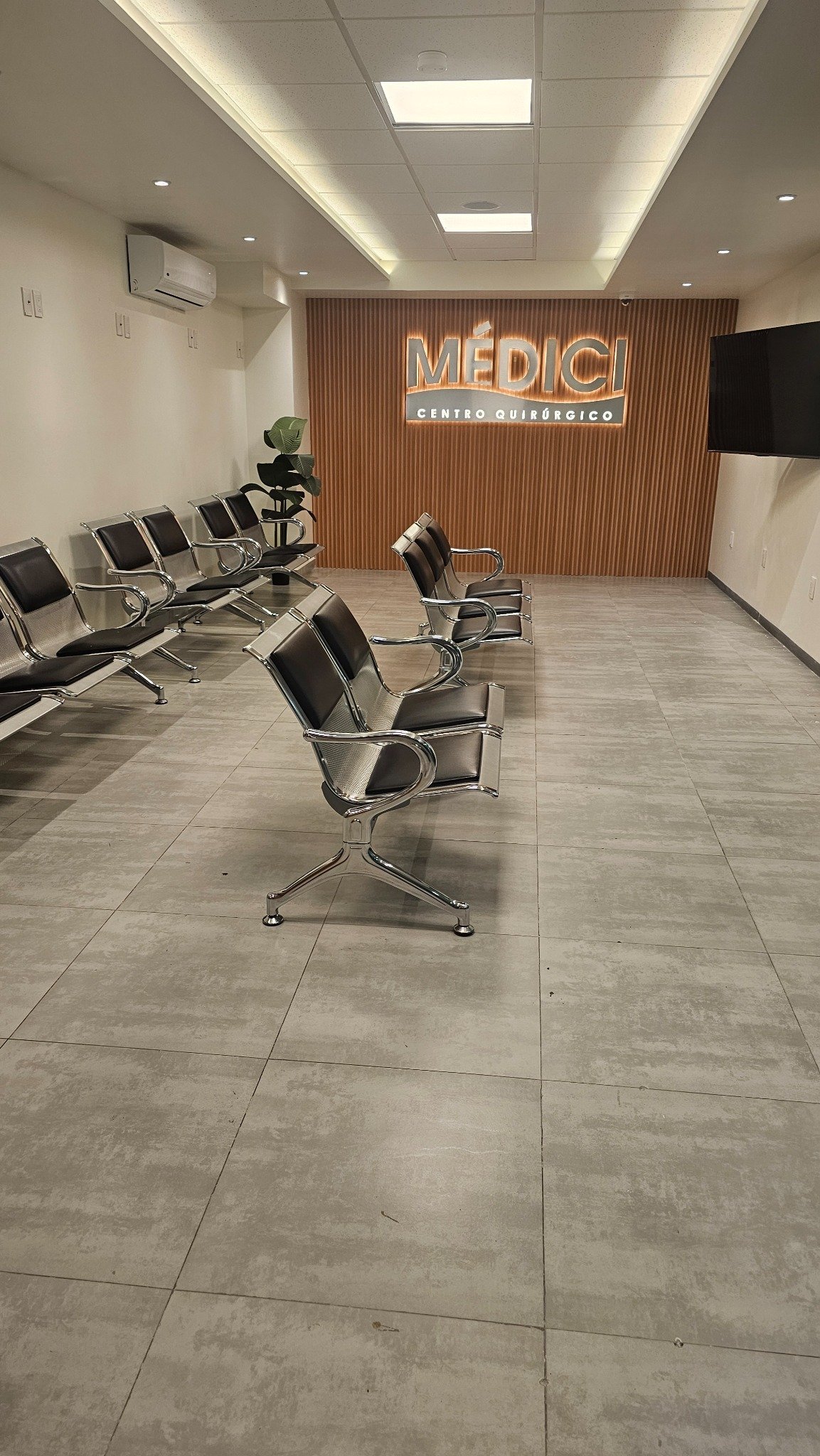 Recepción de Clínica Médici con sillones de espera y muro de madera con el logotipo de la clínica
